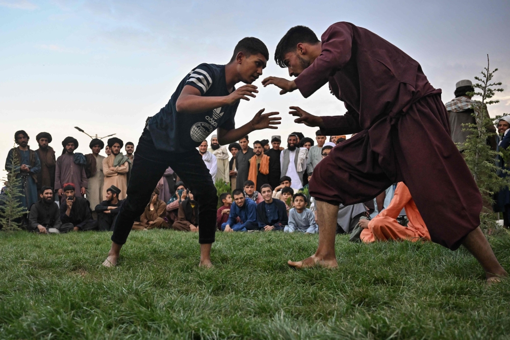  People watch youths taking part in a wrestling match at Wazir Akbar Khan Hill in Kabul on August 12, 2022.