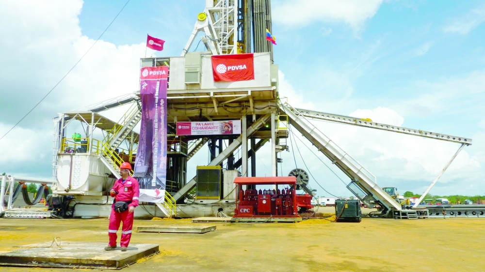 An oilfield worker walks next to drilling rigs at an oil well operated by Venezuela's state oil company PDVSA. — Reuters