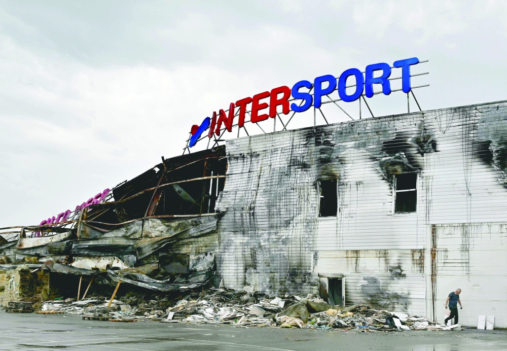 An employee looks through the debris of a destroyed French sporting goods retailer, Intersport, at a shopping mall in Bucha, Kyiv region, on Tuesday. - AFP