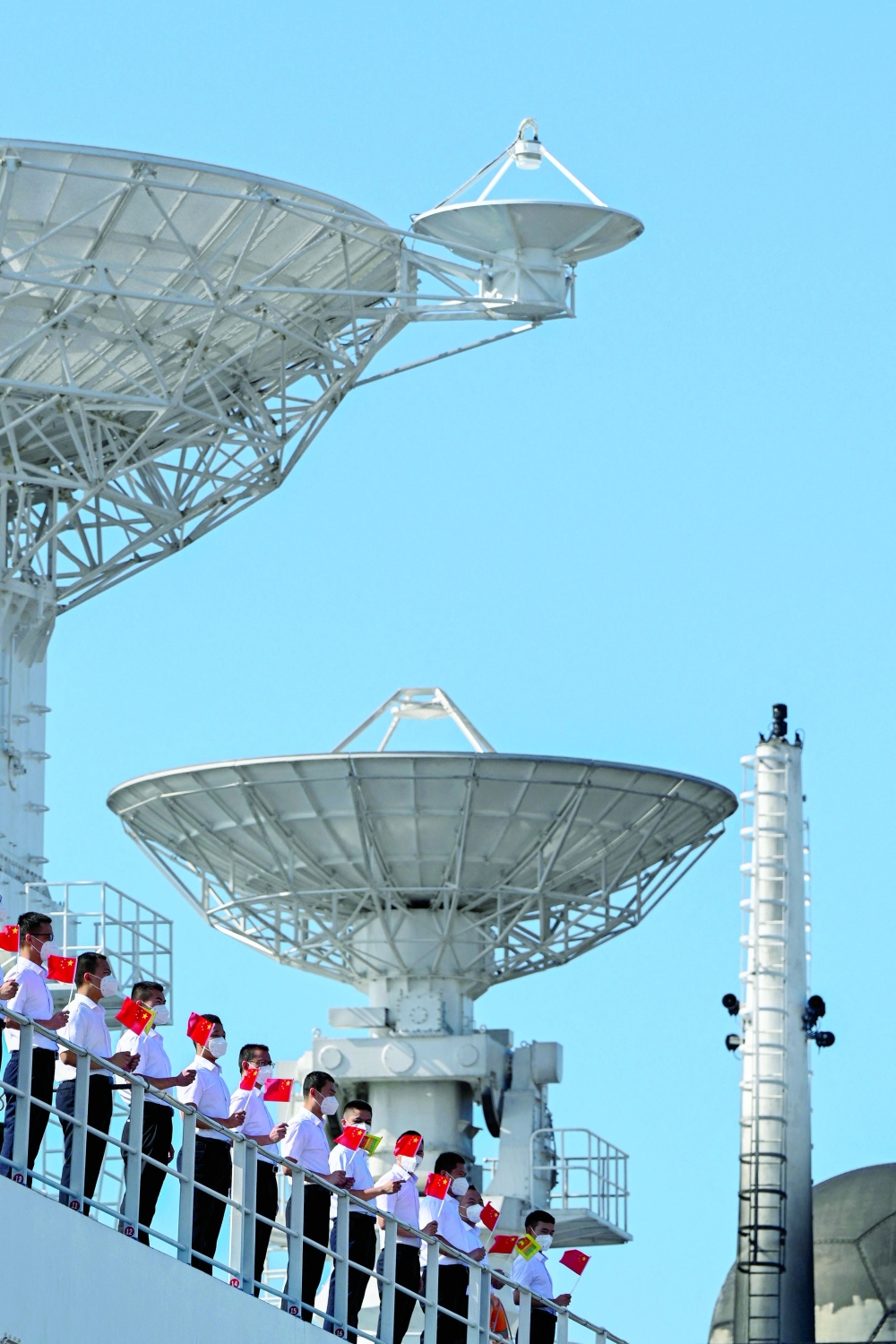 Crew members onboard China's research and survey vessel, the Yuan Wang 5, hold Chinese national flags upon their arrival at Hambantota port on Tuesday. - AFP