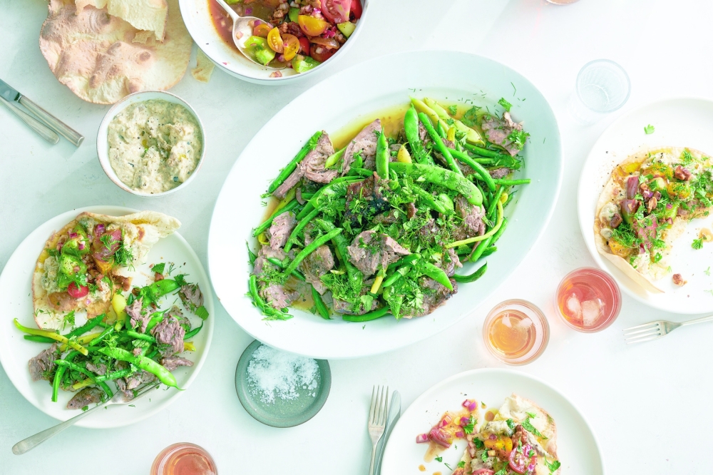 Slow-cooked lamb shoulder with green beans is served with tomato salad and smoky eggplant flatbread in New York, Aug. 4, 2022. Food styled by Simon Andrews. (David Malosh/The New York Times)