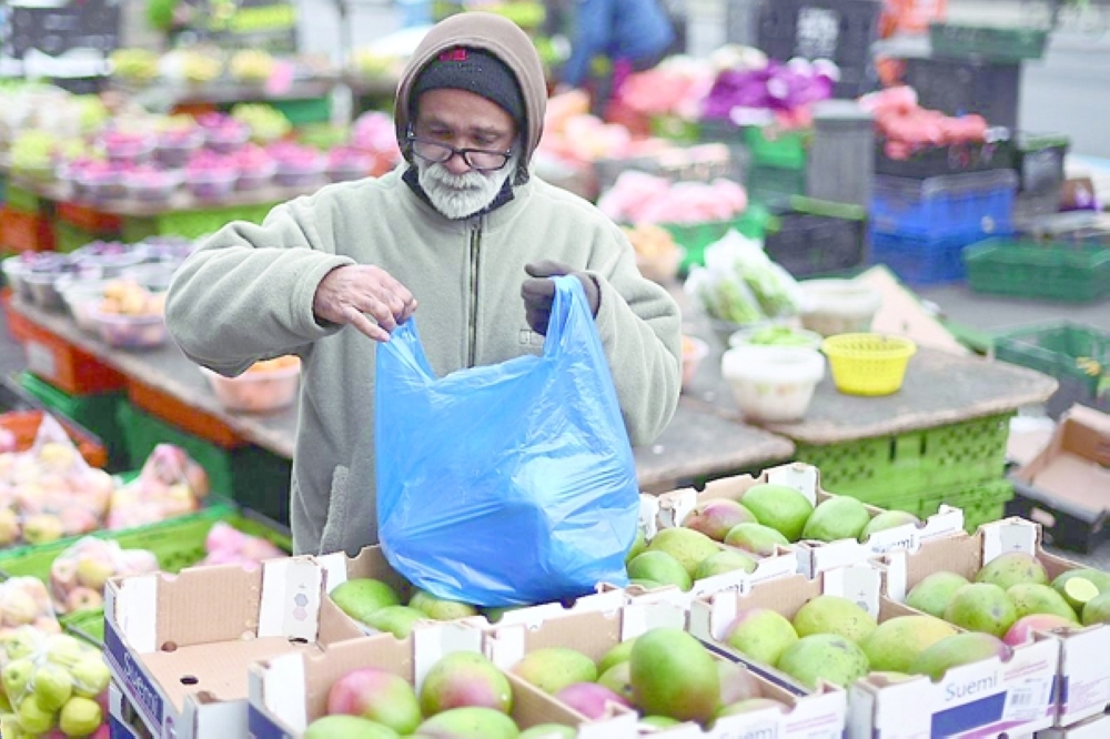 A man purchases fruit on a market stall in London. — AFP