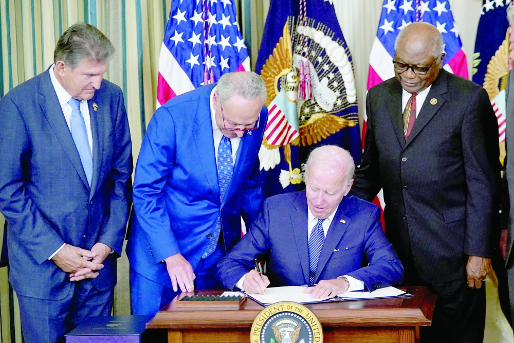 US Senator Joe Manchin (L), US Senate Majority Leader Chuck Schumer (2L)  and House Majority Whip James Clyburn (D-SC) watch US President Joe Biden sign the Inflation Reduction Act of 2022 into law during a ceremony in the State Dining Room of the White House in Washington, DC.  — AFP
