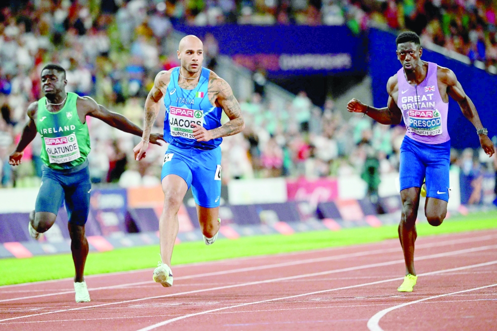 TOPSHOT - Italy's Lamont Marcell Jacobs (C) wins the men's 100m final during the European Athletics Championships at the Olympic Stadium in Munich, southern Germany on August 16, 2022. Italy's Lamont Marcell Jacobs won gold ahead of Britain's Zharnel Hughes and Britain's Jeremiah Azu. (Photo by INA FASSBENDER / AFP)

