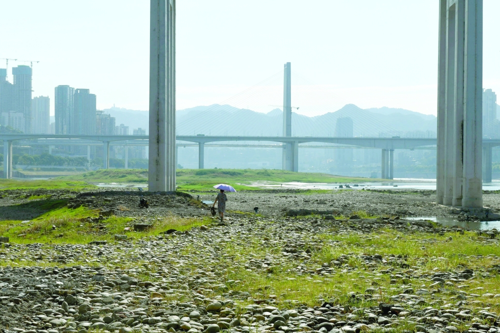 A woman walks on the exposed riverbed of Yangtze river on a hot day in Chongqing on Wednesday. — Reuters