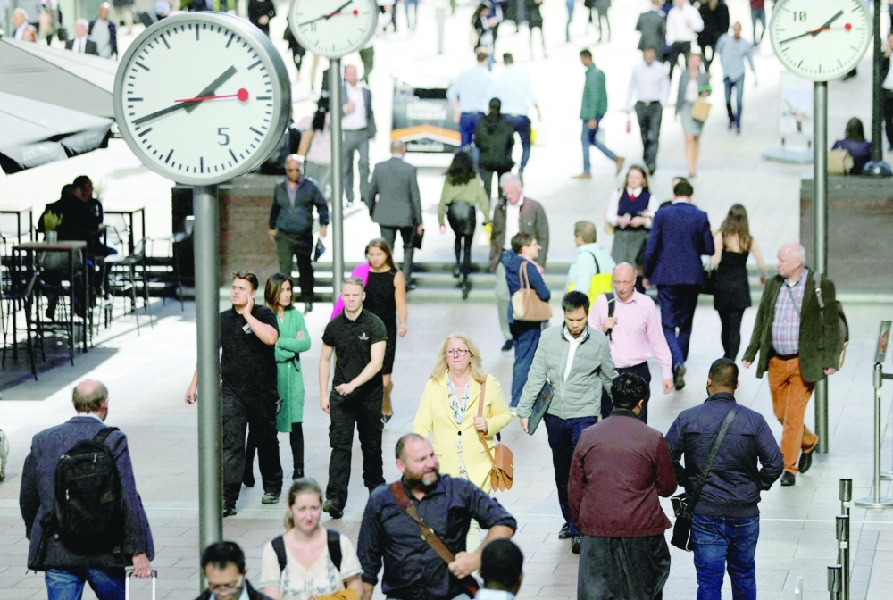 People walk through the financial district of Canary Wharf, London. - Reuters