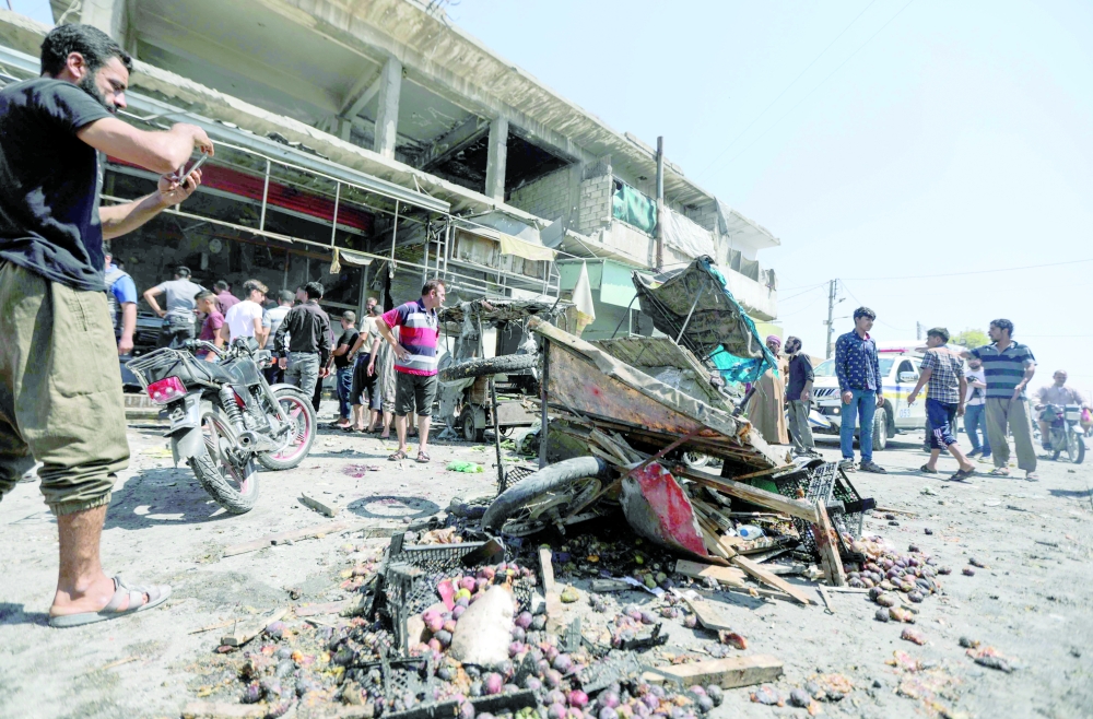 People gather at the sight of a bombing at a busy market in the opposition-held city of Al Bab, on the border with Turkey in Syria's northern Aleppo province, on Friday. - AFP