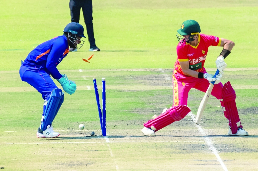 Zimbabwe's Bradley Evans (R) looks back towards his shattered wicket as India's wicketkeeper Sanju Samson looks on during the second one day international (ODI) cricket match between Zimbabwe and India at The Harare Sports Club in Harare on August 20, 2022. (Photo by Jekesai NJIKIZANA / AFP)

