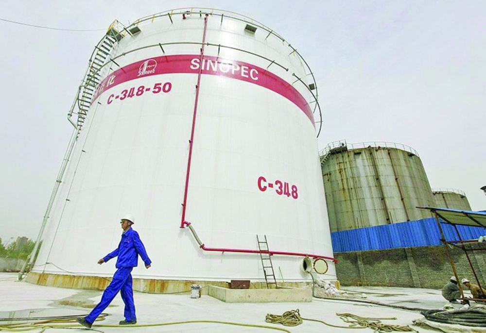 A man walks past oil tanks at a Sinopec refinery in Wuhan, Hubei province.  — Reuters
