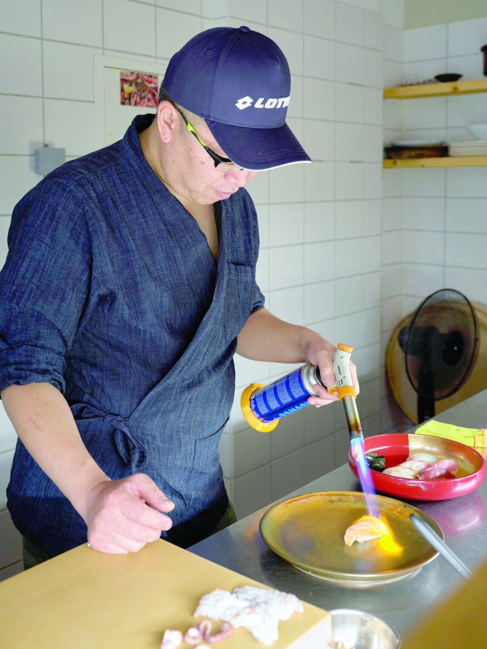 A chef prepares a dish at San, a low-key Japanese restaurant in Berlin, Aug. 12, 2022. (Andreas Meichsner/The New York Times)