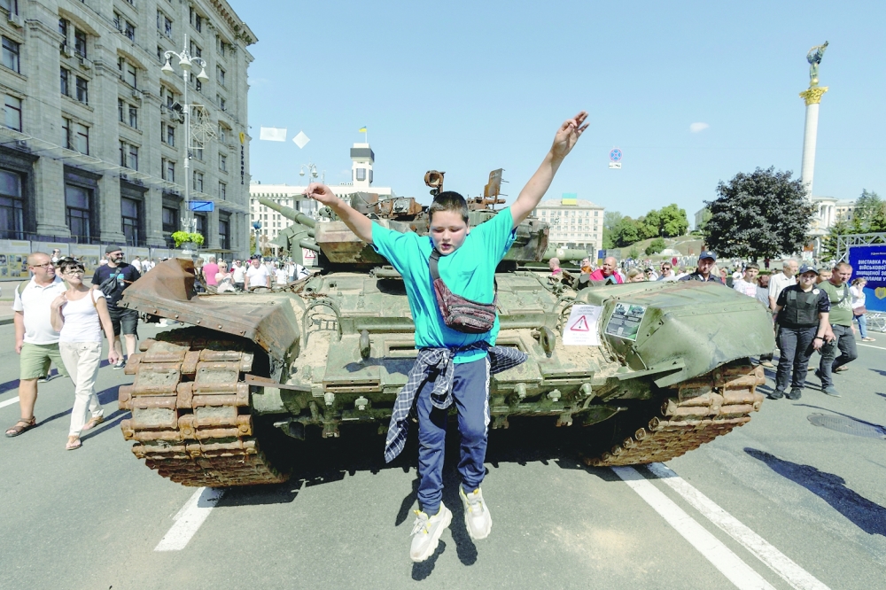 A boy jumps from a tank at an exhibition of destroyed Russian military vehicles and weapons, dedicated to the upcoming country's Independence Day in the centre of Kyiv. - Reuters

