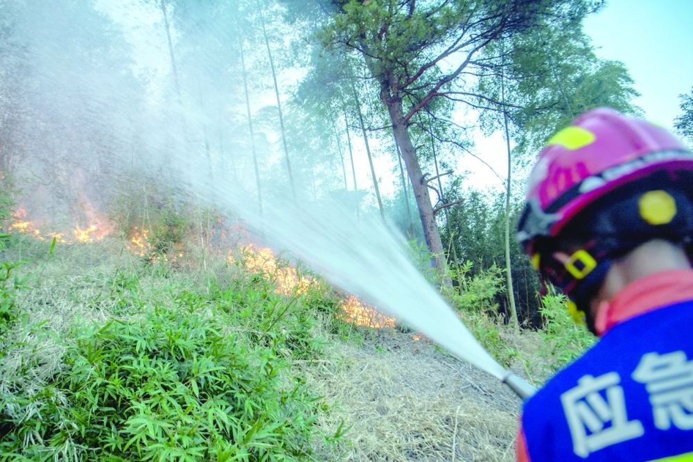 A firefighter puts out wildfire that broke out in a forest amid hot temperatures, in Luzhou, Sichuan province of China, on Monday. - Reuters