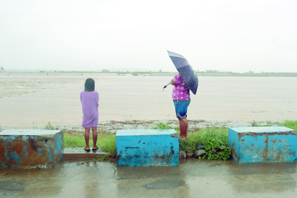 Residents watch the overflowing Pinacanuan River due to heavy rains brought about by tropical storm Ma-on in Ilagan City, Isabela province, on Tuesday. - AFP