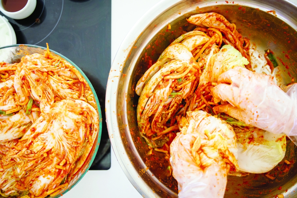 Lauryn Chun, the founder of Mother-in-Law’s Kimchi, prepares kimchi with her mother, left, at their home in Orange, Calif. on Aug. 16, 2022. (Tanveer Badal/The New York Times)