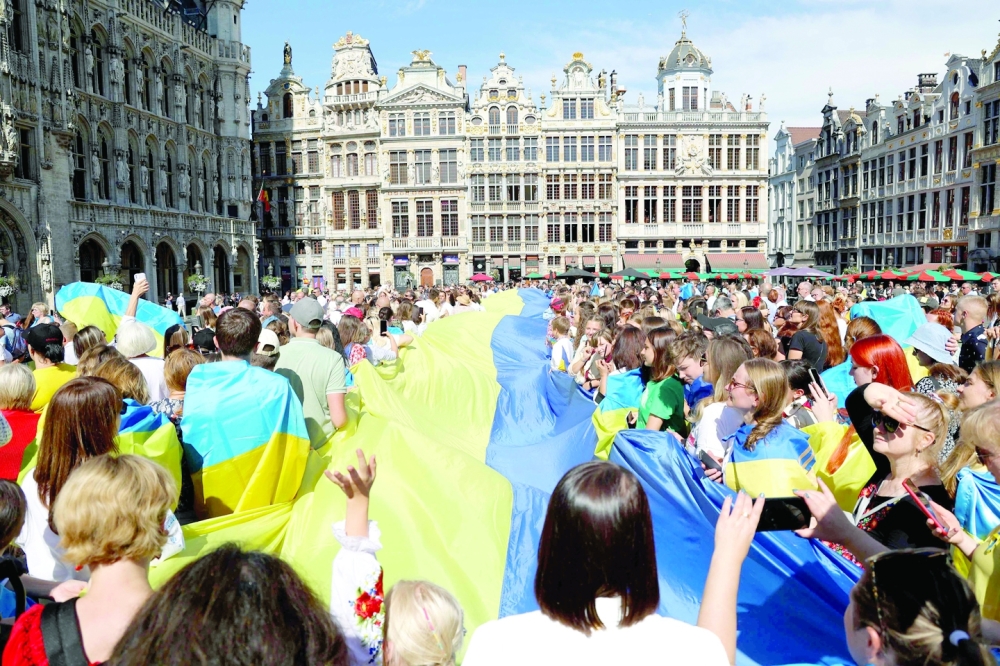 Attendees hold a giant Ukrainian flag as they take part in a ceremony to celebrate Ukraine's Independence Day, on the Grand-Place in Brussels, on Wednesday. -- AFP