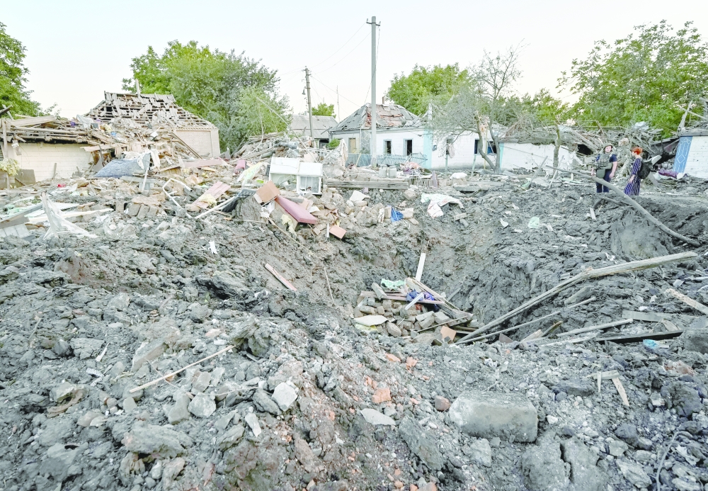 People stand next to a residential house destroyed by a Russian military strike in Chaplyne, Dnipropetrovsk region, Ukraine on Wednesday. -- Reuters