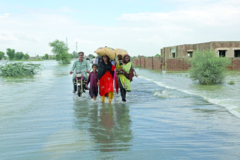 Stranded people wade through a flooded area after heavy monsoon rainfall in Rajanpur district of Punjab province, Pakistan, on Thursday. Figures from the national disaster agency showed that 903 people had died in the floods since June, and over 180,000 were forced to flee their rural homes. - AFP

