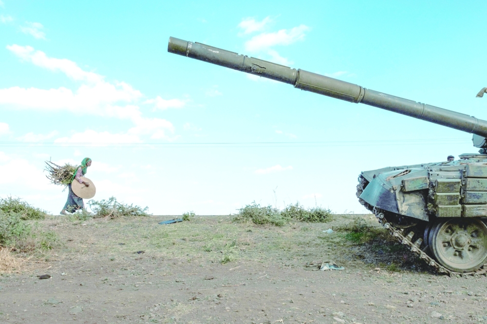 A woman carrying crops walks next to an abandoned tank belonging to Tigrayan forces south of the town of Mehoni, Ethiopia. - AFP file photo