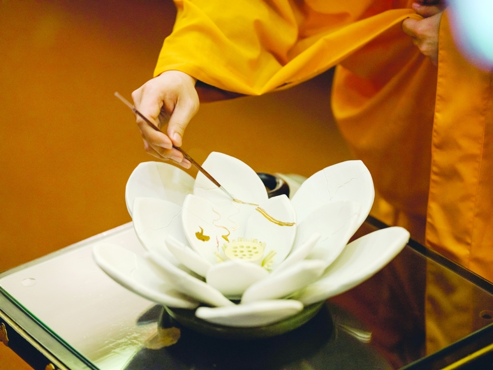 Performing kintsugi on a cracked ceramic lotus flower in Los Angeles, May 4, 2021. (Rozette Rago/The New York Times)