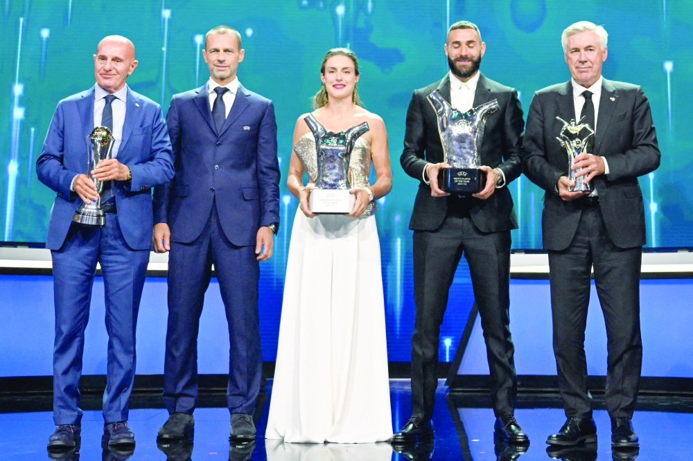 Former head coach of the Italian national football team and twice manager of AC Milan Arrigho Sacchi (L) holding his "Best President Award", UEFA president Aleksander Ceferin, Barcelona's Spanish forward Alexia Putellas holding her "Women's Best Player Award" for the 2021/2022 season, Real Madrid's French forward Karim Benzema holding his "Men's Best Player Award" and Real Madrid's Italian coach Carlo Ancelotti holding his "Men's Best Coach Award" stand on stage in Istanbul on August 25, 2022, after the 2022/2023 Champions League group stage draw. (Photo by OZAN KOSE / AFP)

