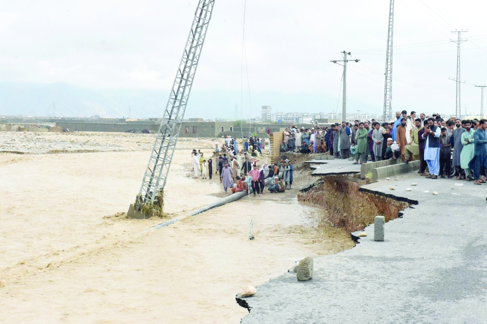 People gather along a road damaged by flooding after heavy monsoon rainfalls in Quetta on Friday. - AFP