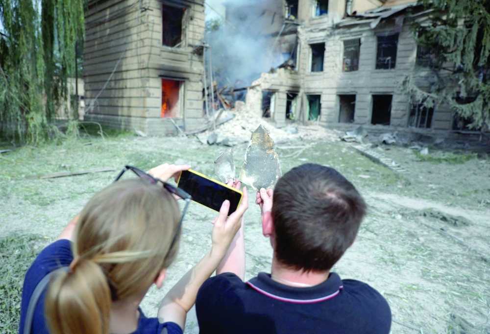 Local residents photograph a missile fragment in front of a destroyed college building following an air strike on the town of Sloviansk, Donetsk region, on Friday. - AFP