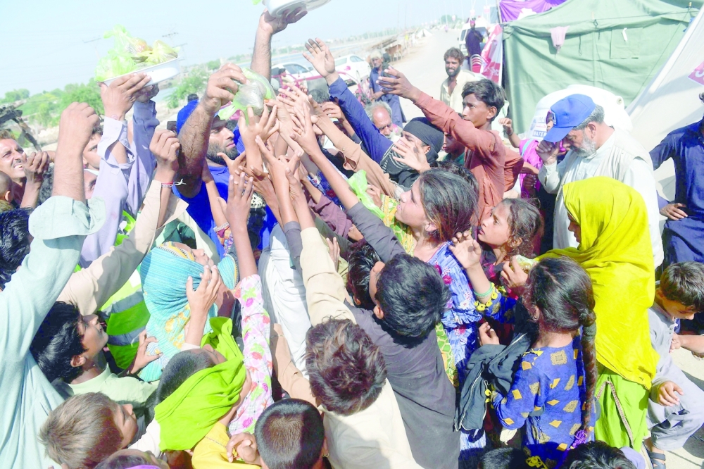 Volunteers of the Charity Al Khidmat Foundation distribute food bags to flood-affected children at a makeshift camp in Sukkur, Sindh province, on Thursday. - AFP