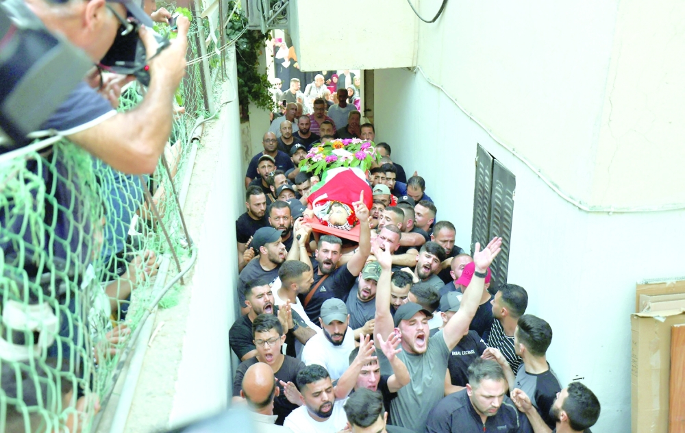 Palestinian mourners carry the body of Yazan Afana, 26, from Qalandia camp outside Jerusalem, who died after being shot during clashes with Israeli forces, during his funeral procession on Thursday. - AFP