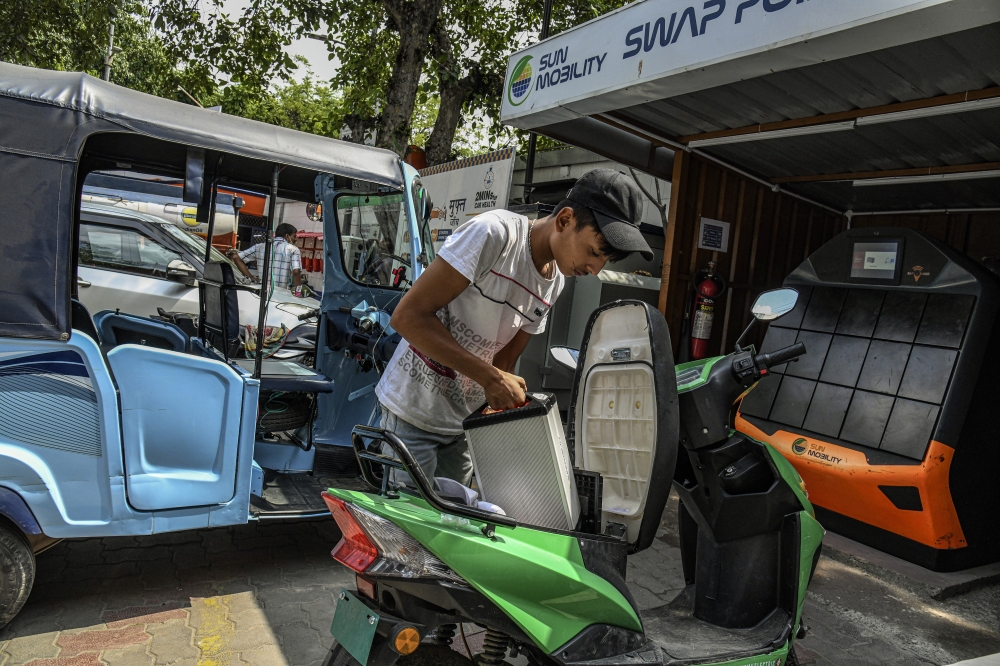 A rider places a fresh battery in his electric moped at a Sun Mobility swapping station in New Delhi, Aug. 26, 2022. (Atul Loke/The New York Times)