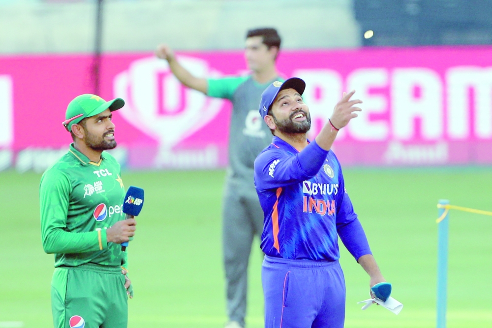 Pakistan's captain Babar Azam (L) watches India's captain Rohit Sharma tossing a coin before the start of the Asia Cup Twenty20 international cricket Super Four match between India and Pakistan at the Dubai International Cricket Stadium in Dubai on September 4, 2022. (Photo by Surjeet Yadav / AFP)

