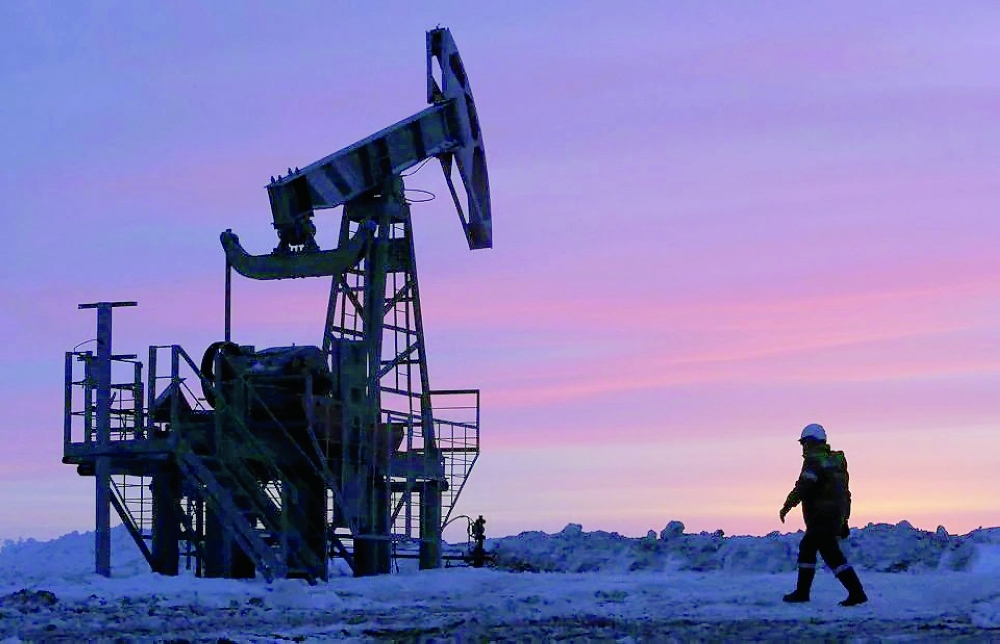 A worker walks past a pump jack on an oil field near the village of Nikolo-Berezovka, northwest from Ufa, Bashkortostan, Russia.  — Reuters