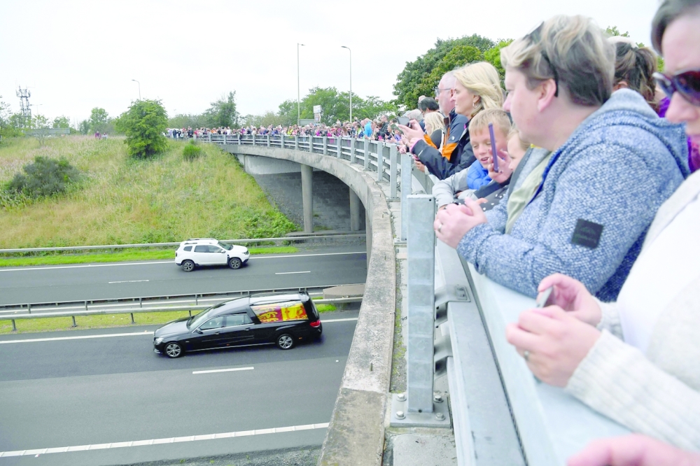 Members of the public stand on a bridge, in Kinross, pay their respects as they wait for the hearse carrying the coffin of Queen Elizabeth II to be driven to Edinburgh to lie at rest. - AFP