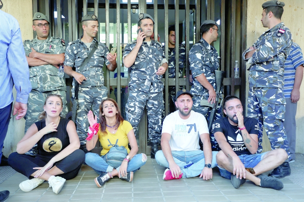 Depositors sit outside an LGB Bank branch in Beirut. -- Reuters