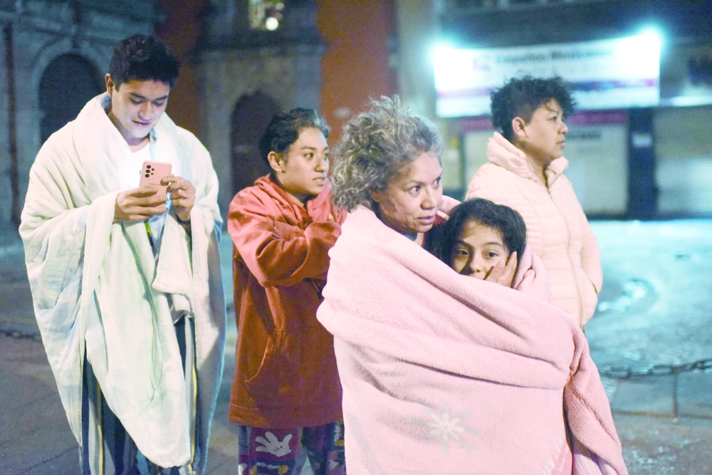 Residents stand in a street after a 6.8-magnitude earthquake in Mexico City. -- AFP
