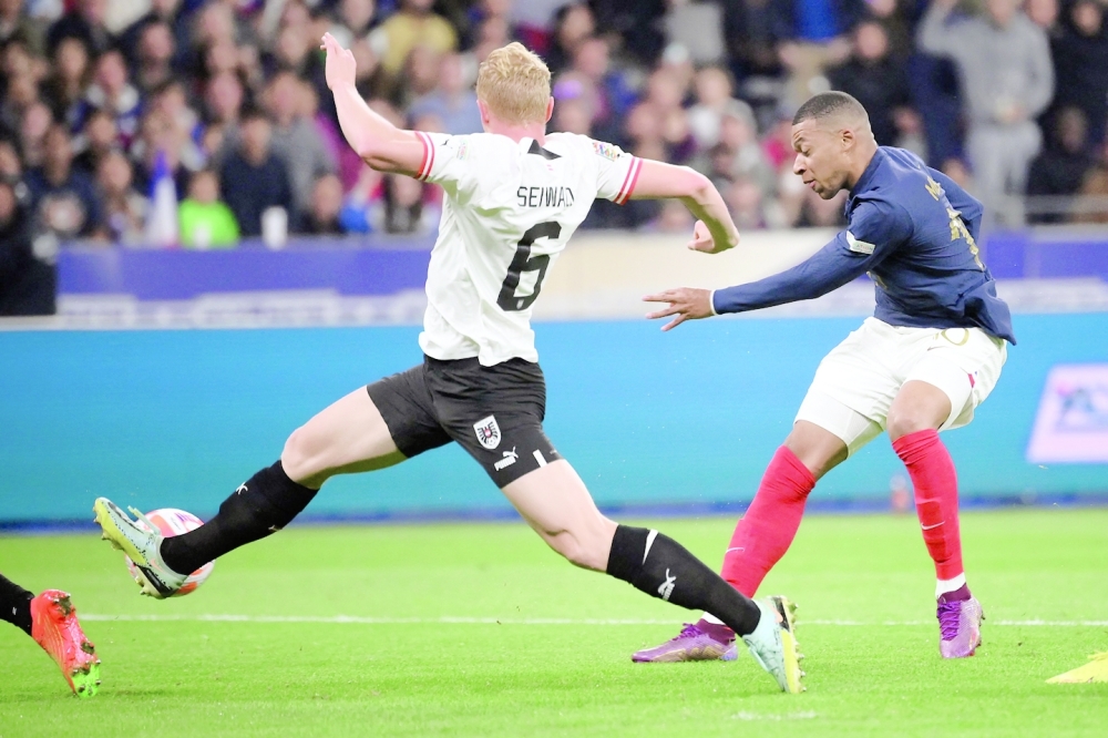 TOPSHOT - France's forward Kylian Mbappe (R) shoots and scores his team's first goal during the UEFA Nations League, League A Group 1 football match between France and Austria at Stade de France in Saint-Denis, north of Paris, on September 22, 2022. (Photo by FRANCK FIFE / AFP)

