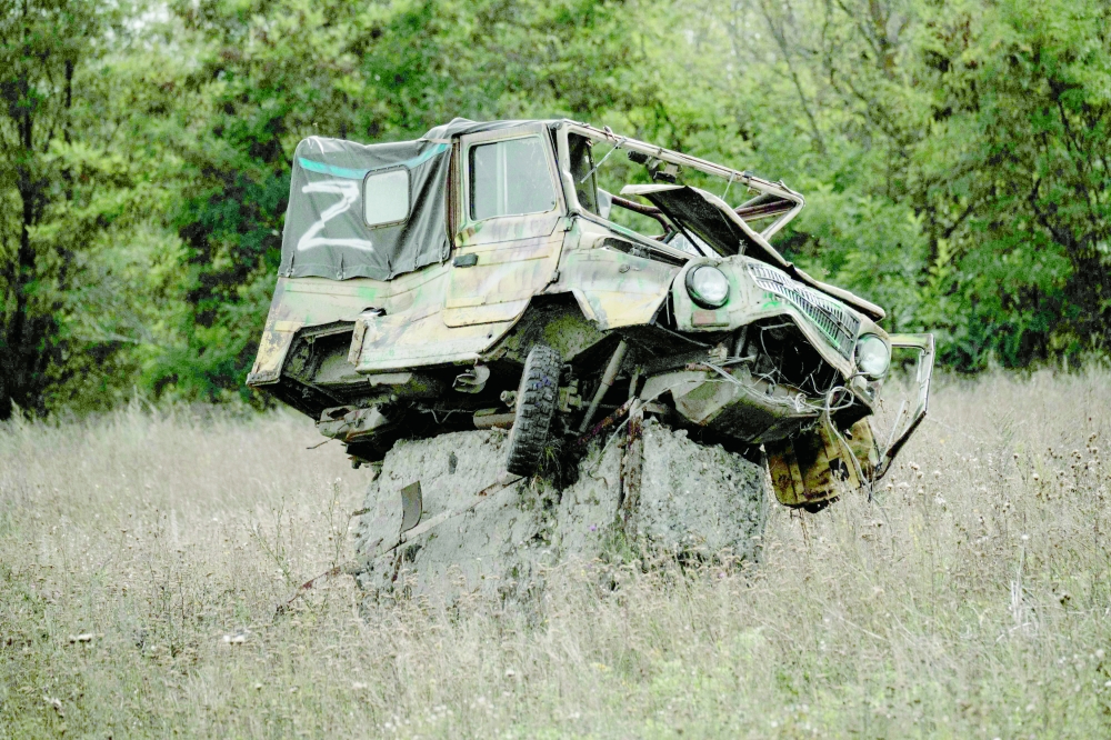A damaged car bearing the letter Z, at a possible mine field next to an abandoned industrial chicken farm, near a suspected mass grave in Kozacha Lopan, Kharkiv region. - AFP