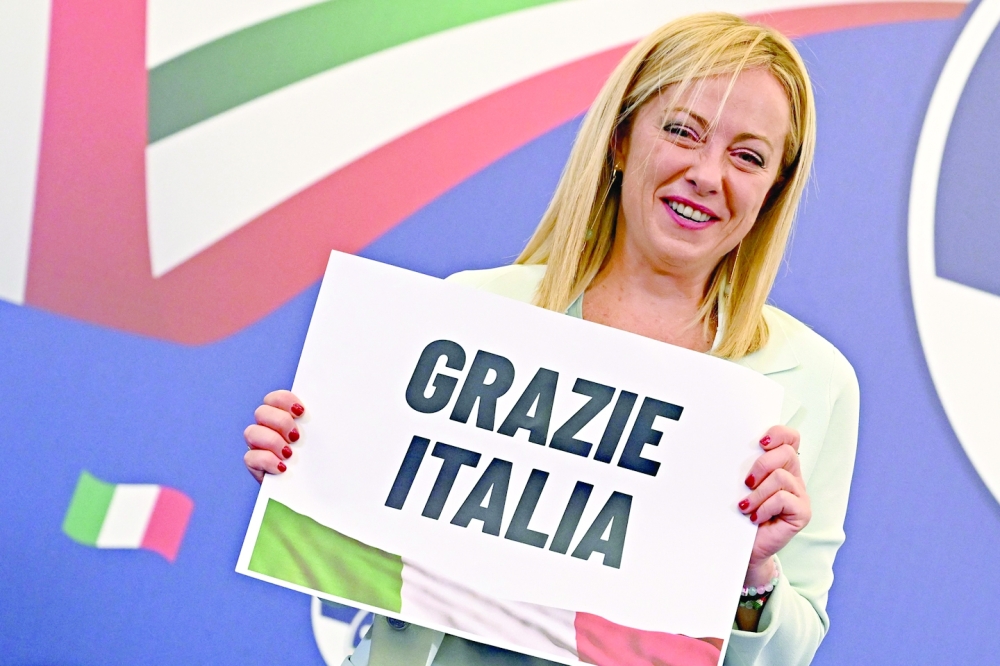 Leader of Italian far-right party Brothers of Italy, Giorgia Meloni, holds a placard reading 'Thank You Italy' after she delivered an address at her party's campaign headquarters in Rome. - AFP