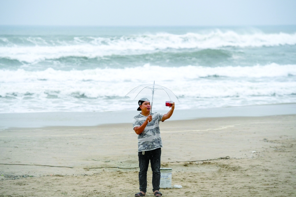 A man takes a selfie picture under his umbrella on a beach in Danang. - AFP