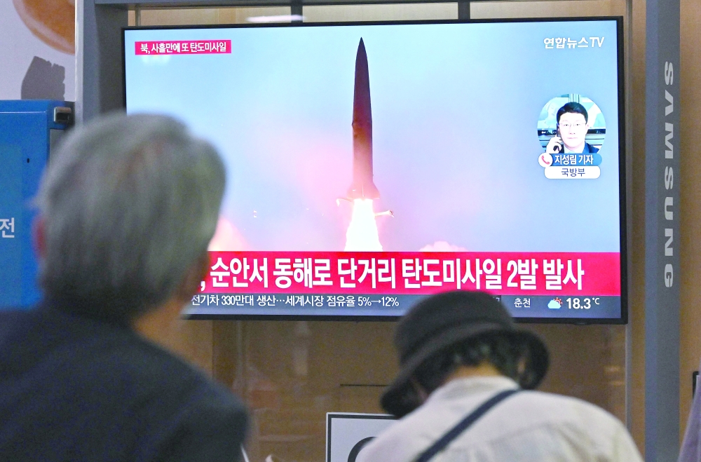 People watch a television screen showing a news broadcast with file footage of a North Korean missile test at a railway station in Seoul. - AFP