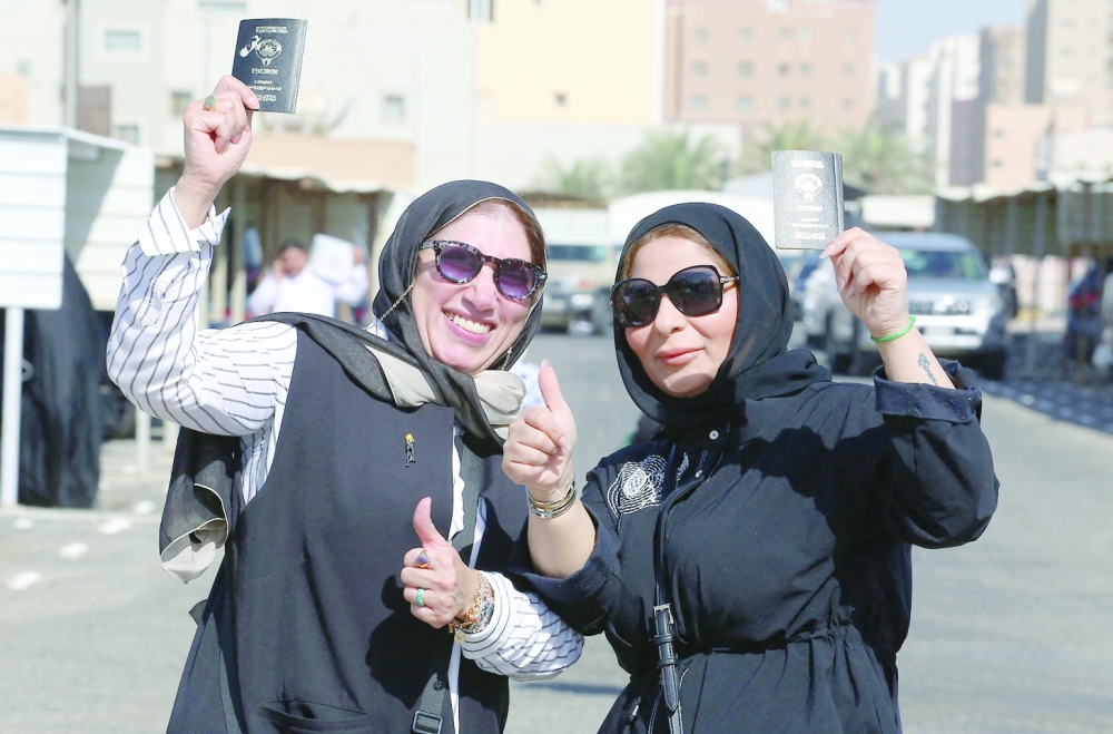 Women display their passports as they vote during parliamentary elections in Kuwait City on Thursday. — AFP