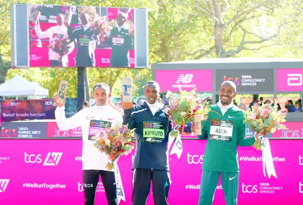 Athletics - London Marathon - London, Britain - October 2, 2022 Kenya's Amos Kipruto celebrates on the podium after winning the men's elite race alongside second place Ethiopia's Leul Gebresilase and third place Belgium's Bashir Abdi Action Images via Reuters/Andrew Boyers
