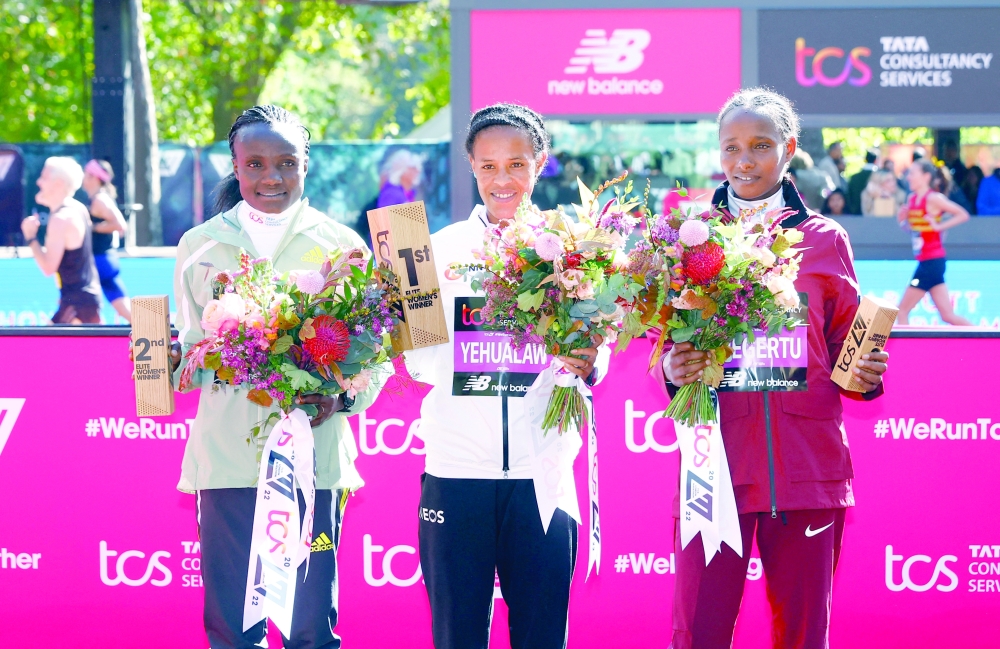 Athletics - London Marathon - London, Britain - October 2, 2022 Ethiopia's Yalemzerf Yehualaw celebrates on the podium after winning the women's elite race alongside second place Kenya's Joyciline Jepkosgei and third place Ethiopia's Alemu Megertu Action Images via Reuters/Andrew Boyers

