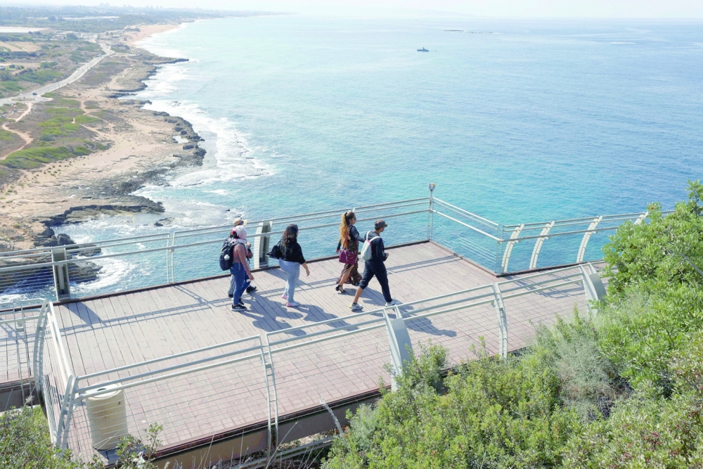 People walk in a visitors area overlooking the Mediterranean Sea in Rosh Hanikra, at the border between Lebanon and Israel. -- AFP
