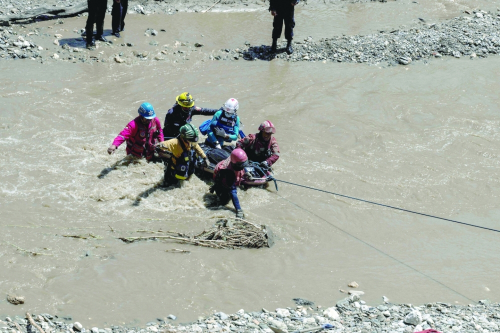 Rescuers from different firefighting and Red Cross institutions cross the Tuy River after a devastating landslide in the Venezuelan town of Las Tejerias. - AFP