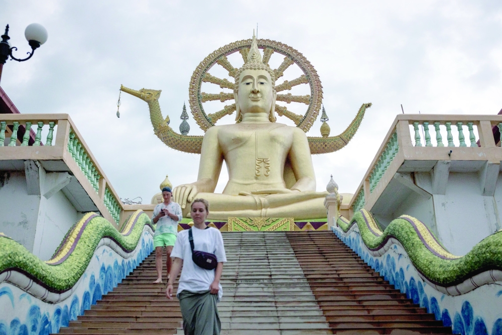 Tourists walk down steps in front of the Big Buddha statue in Koh Samui, Thailand, on Sept. 3, 2022. (Jack Taylor/The New York Times)