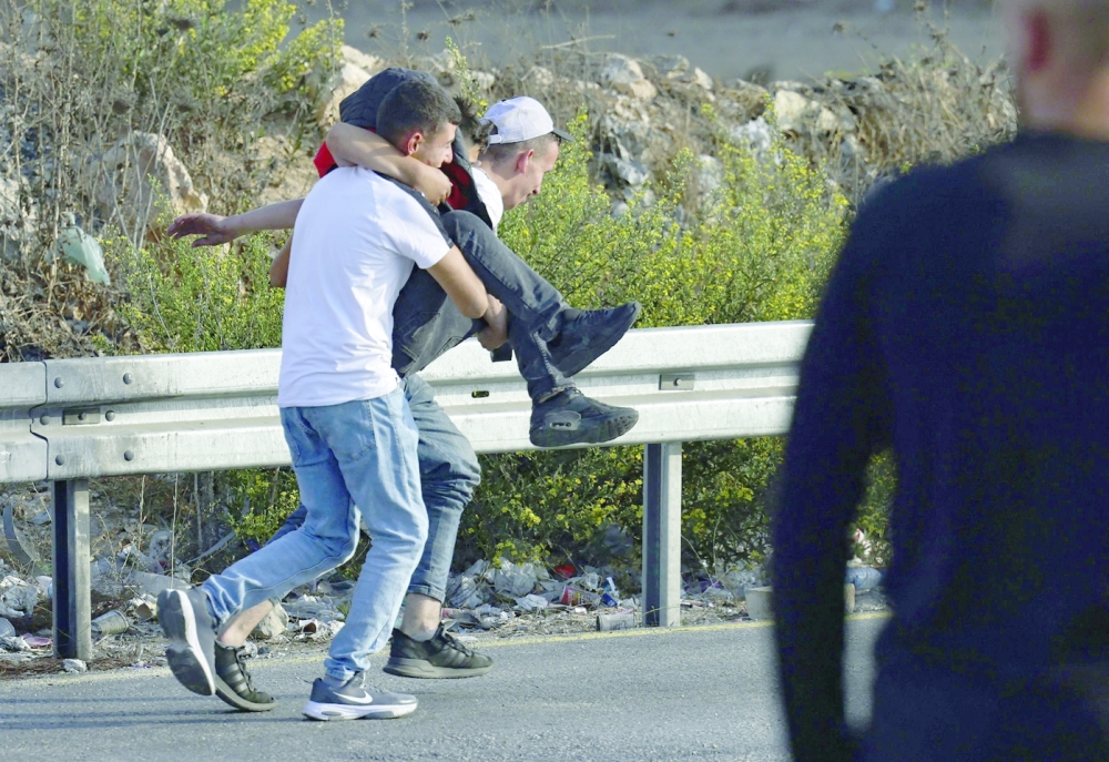Palestinian youths carry a fellow protester, injured during confrontations with Israeli security forces at the northern entrance of the occupied West Bank city of Ramallah. -- AFP

