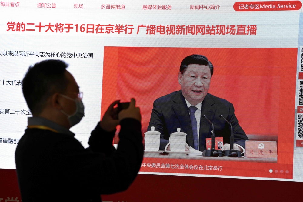 A journalist takes a photo of a screen showing Chinese President Xi Jinping at the press centre ahead of China's 20th Communist Party Congress in Beijing on October 15, 2022.