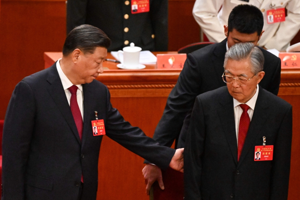 China's President Xi Jinping (L) helps former president Hu Jintao (front R) to his seat during the opening session of the 20th Chinese Communist Party's Congress at the Great Hall of the People in Beijing on October 16, 2022. (Photo by Noel CELIS / AFP)