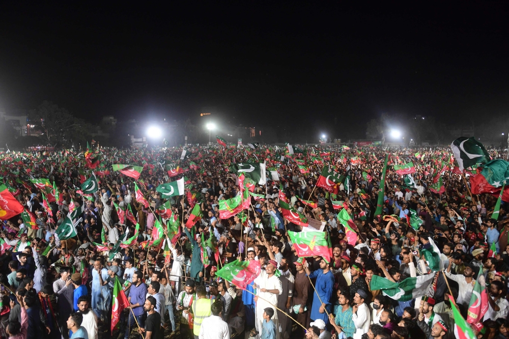 Supporters of Pakistan's former Prime Minister Imran Khan listen to Khan's speech during a by-election campaign meeting in Karachi.  