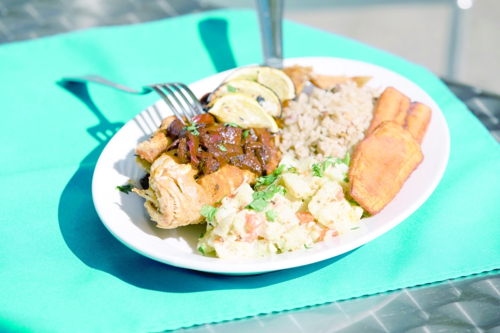A fried fish with coconut rice, pigeon peas, potato salad and plantains dish at El Carnaval in New York on Sept. 28, 2022. (José A. Alvarado Jr./The New York Times)